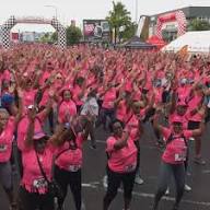 Participants aux Foulées du Ruban Rose levant les bras dans une foule vêtue de rose